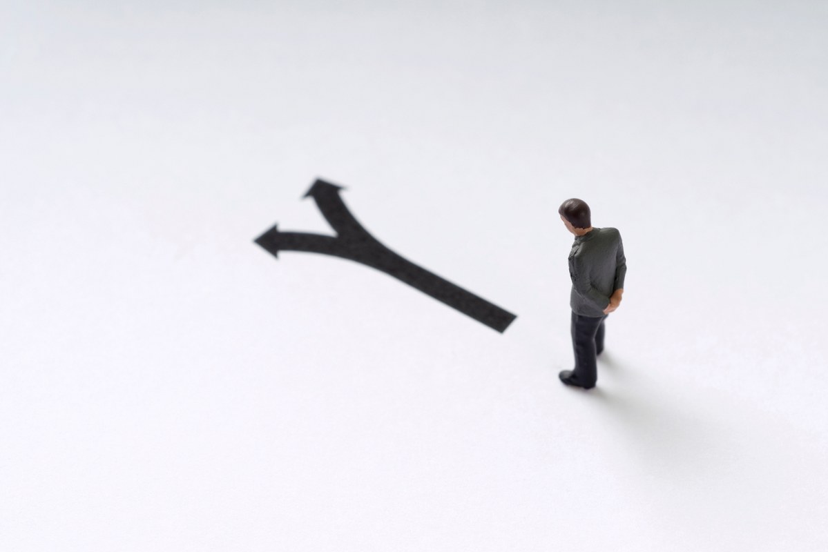 Man figurine deciding which direction to take.