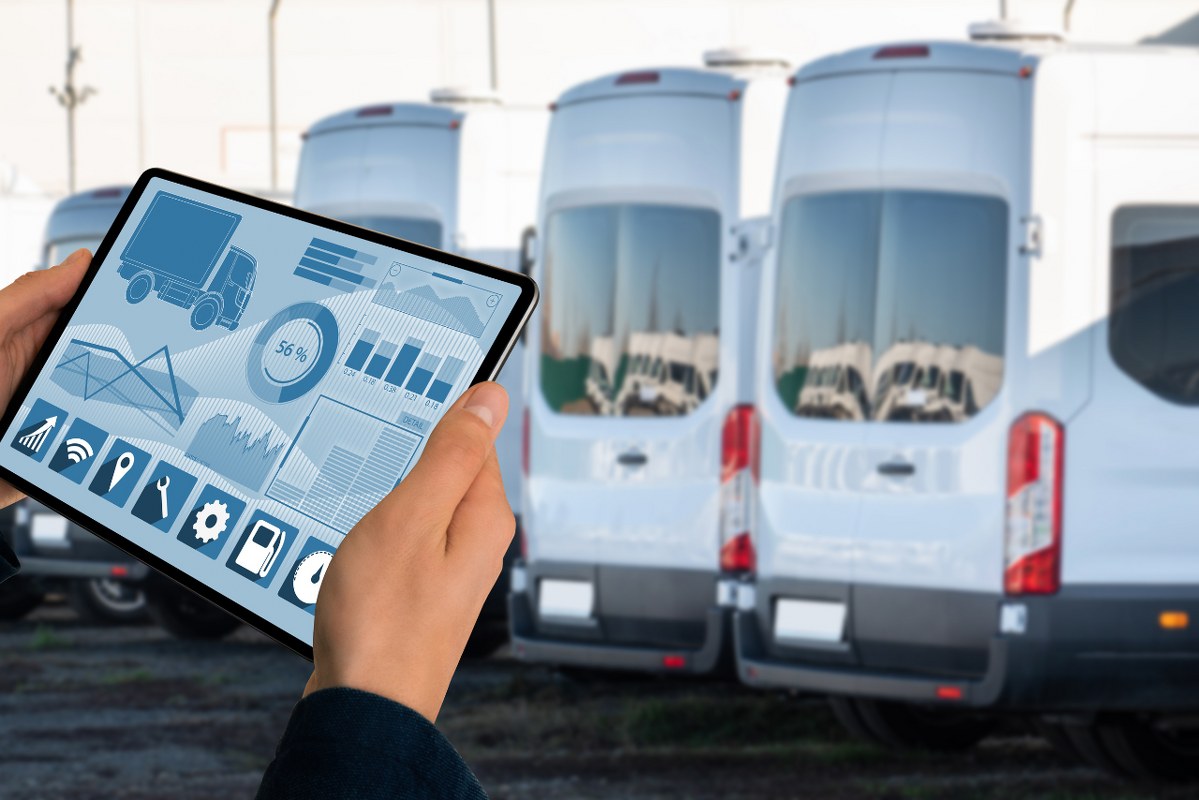 Manager with tablet and using a fleet management tool on background of trucks.