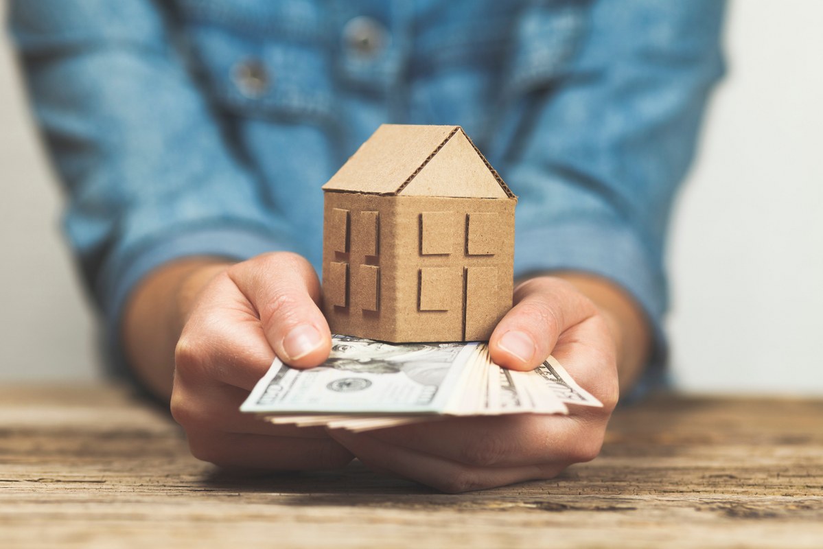 Money and a house held by hands. 
