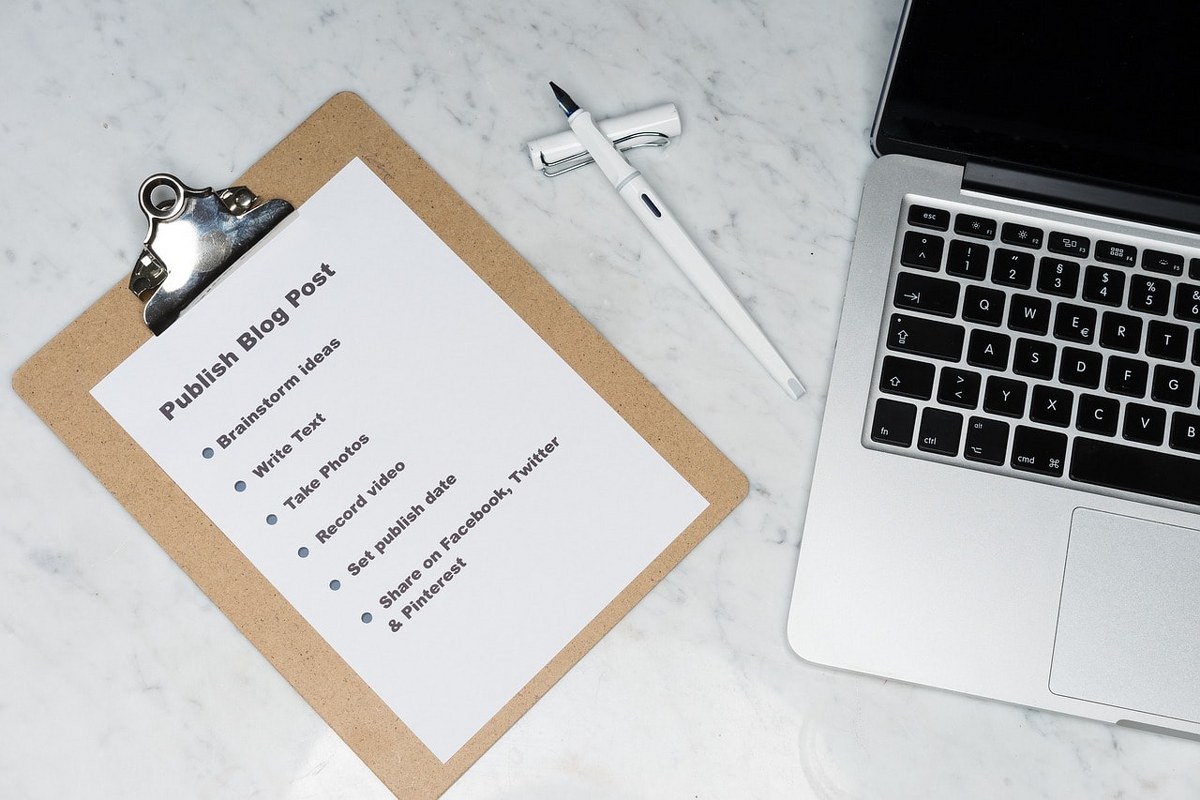 Planning to write a good marketing blog with a clipboard and a laptop.