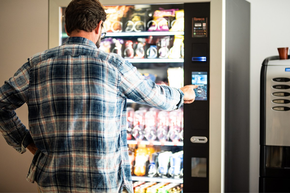 Rear View Of Man Using compact Vending Machine