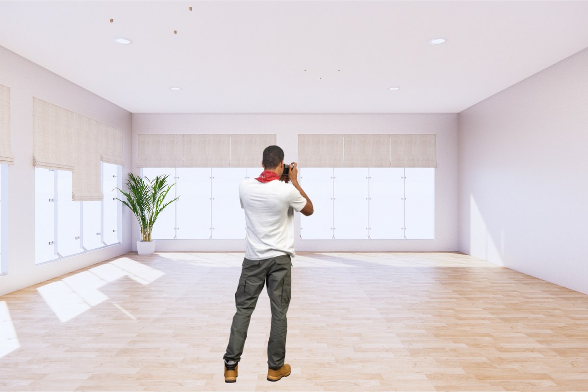 Rearview of man taking photos inside room with natural bright light.