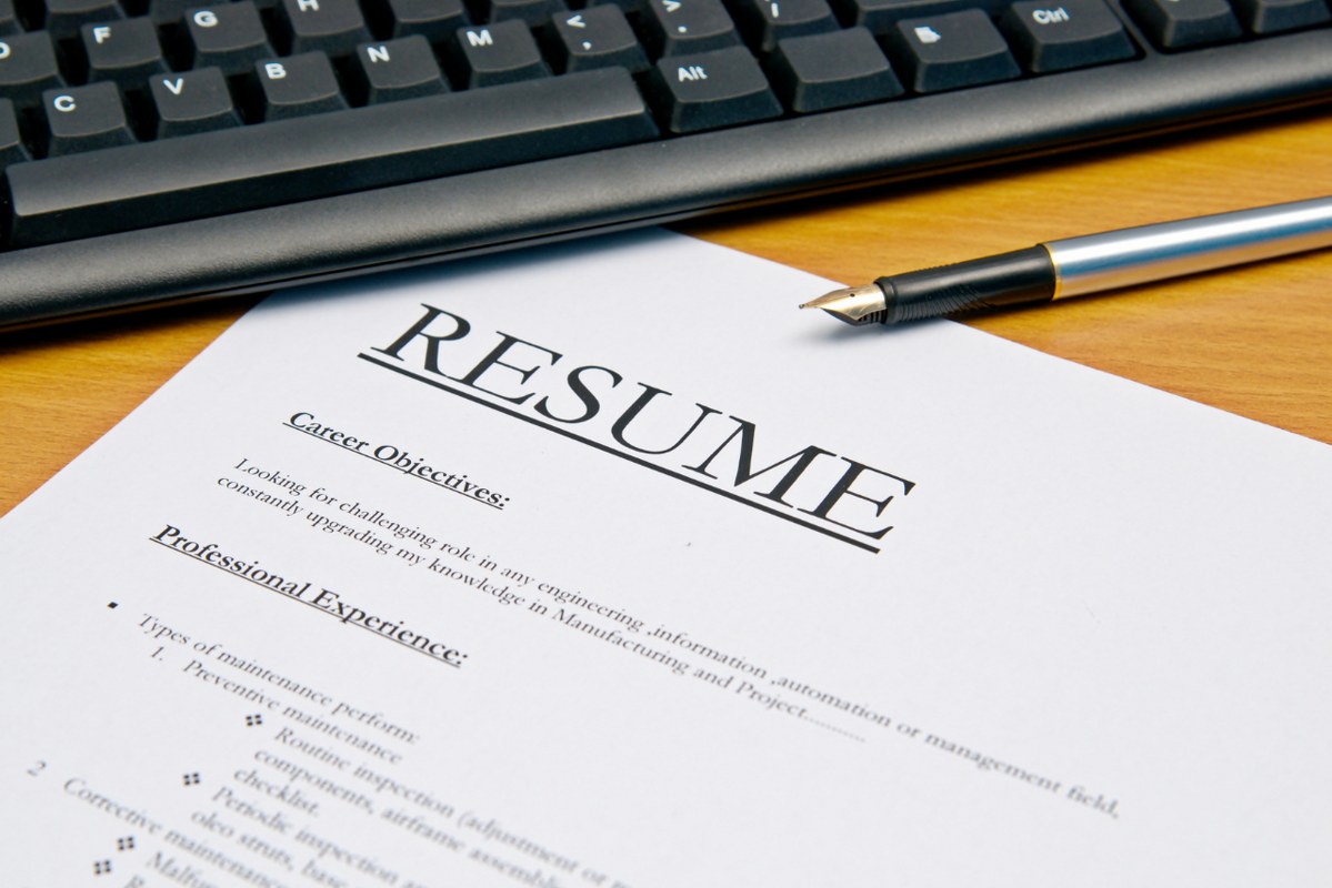 Resume letter on computer desk next to keyboard and pen.