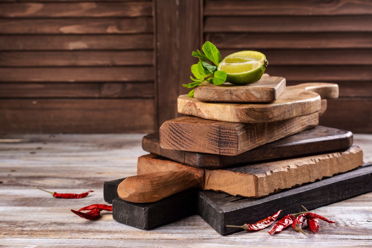Stack of wooden Cutting Boards on top of kitchen table.