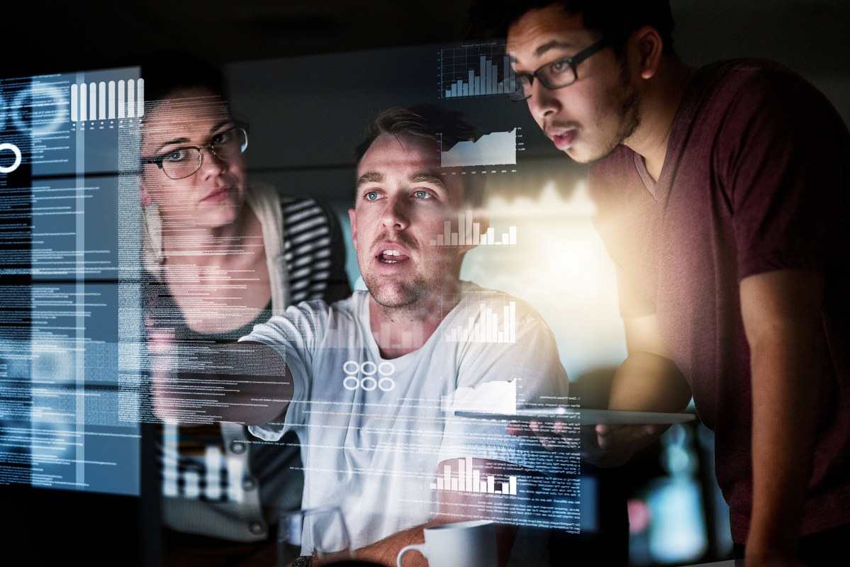 Three marketers analyzing data on hologram.