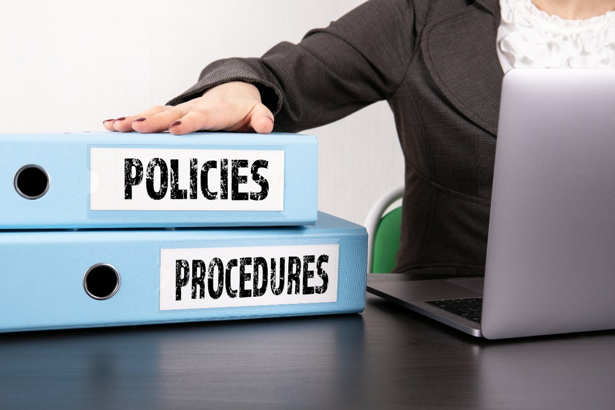 Two binders with policies and procedures written on it, sitting on top of table.