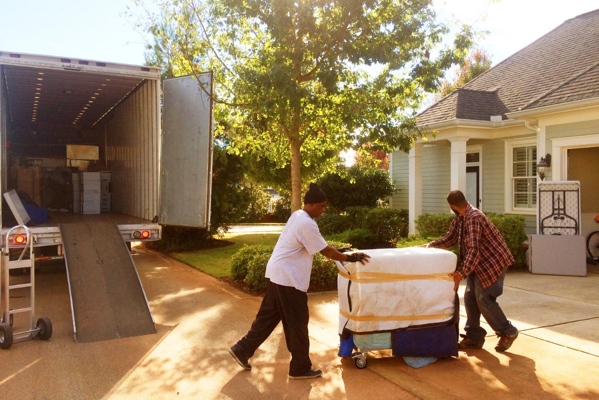 Two moving workers are loading a truck.