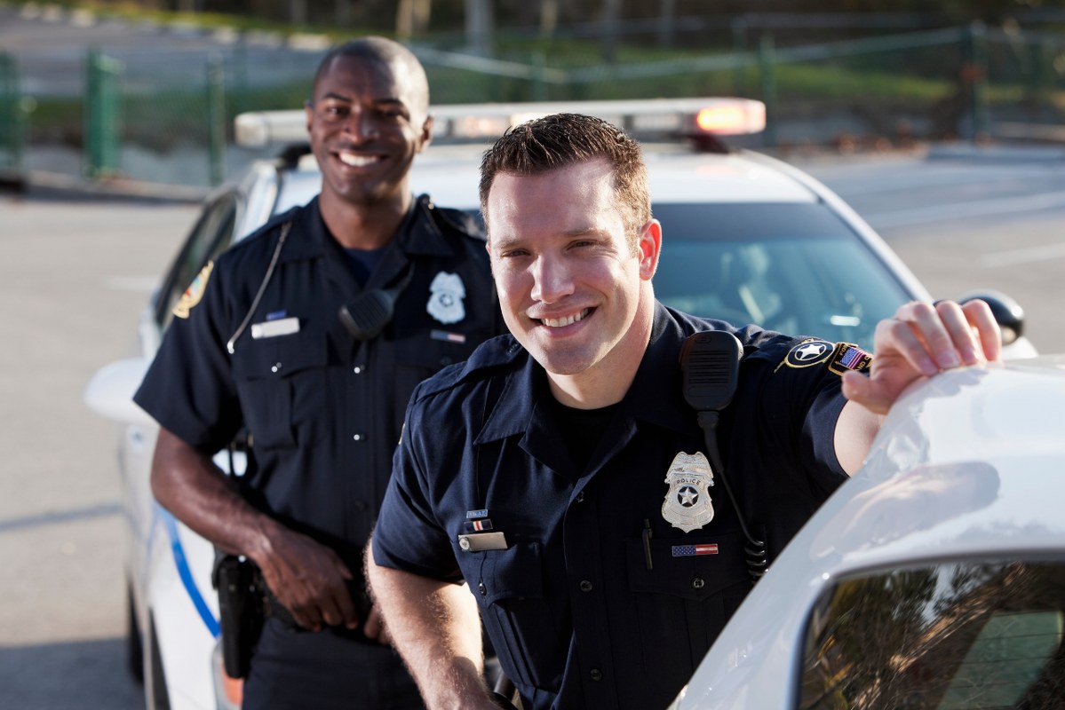Two police officers standing infront of car.