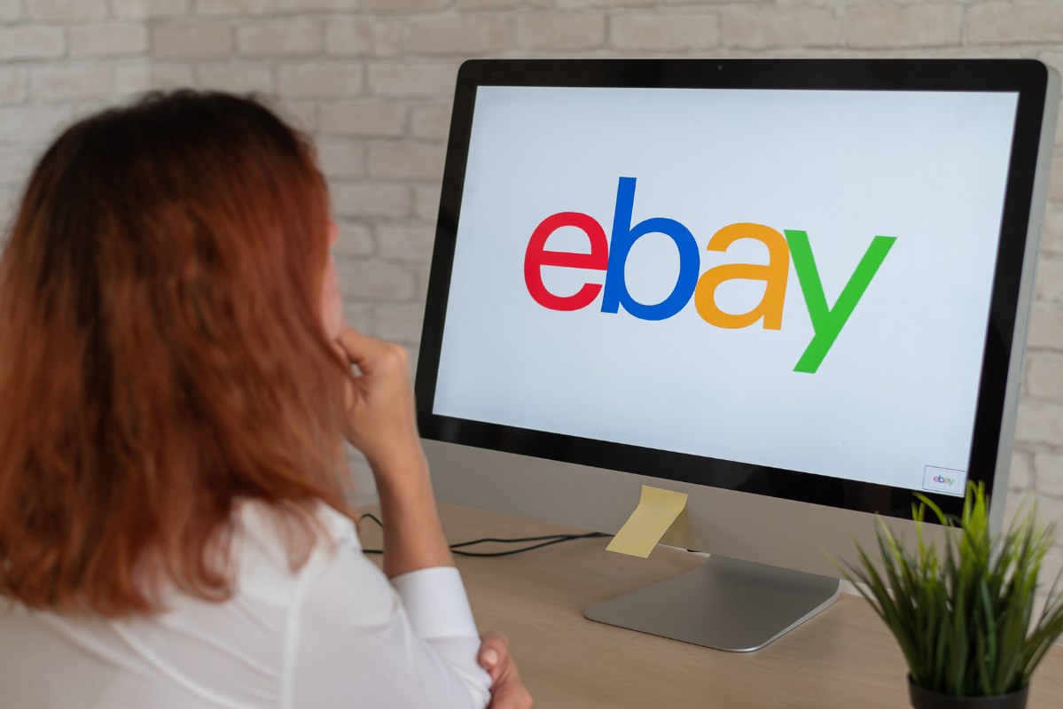 Woman Sitting in Front of Computer Ebay Logo on Screen.