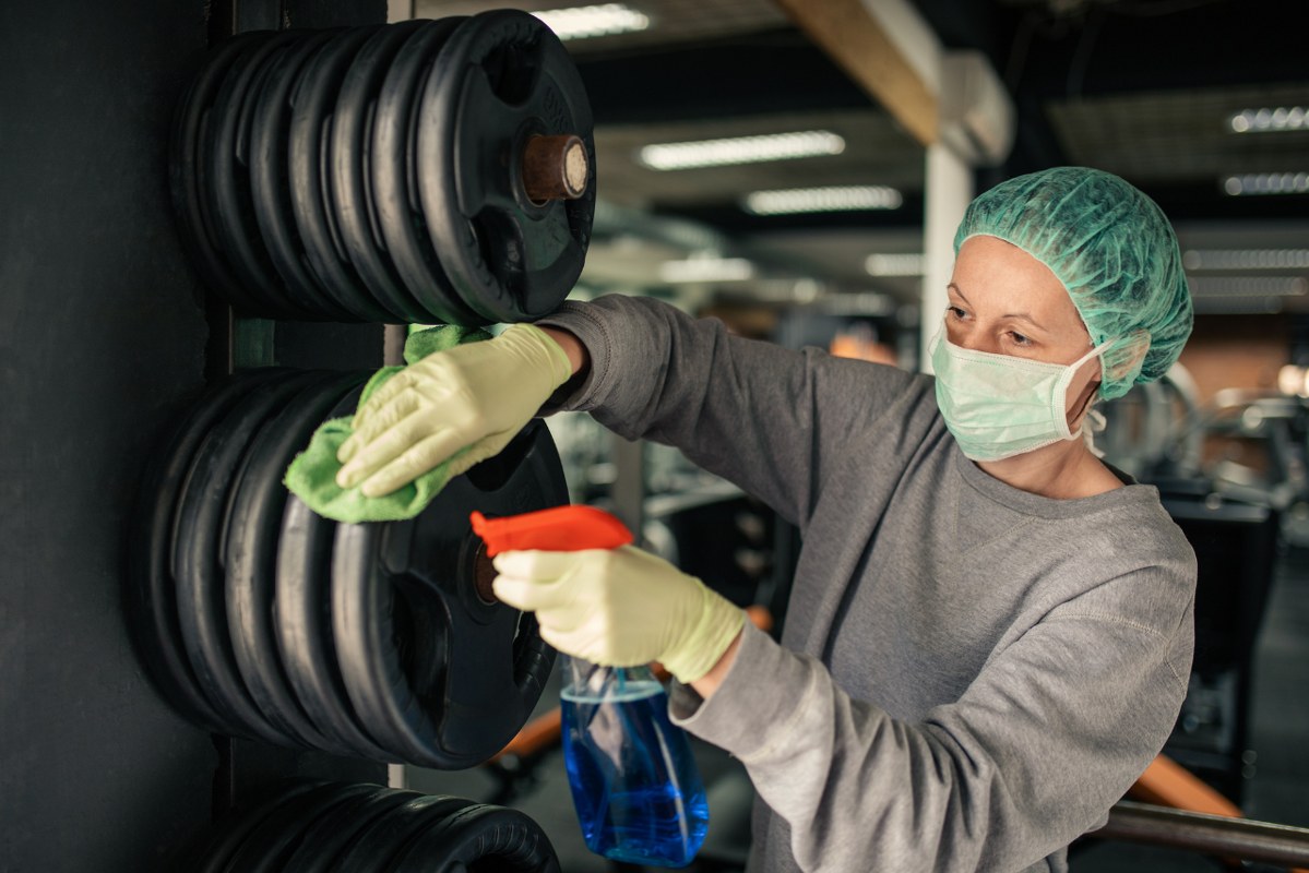Woman disinfecting and cleaning gym.