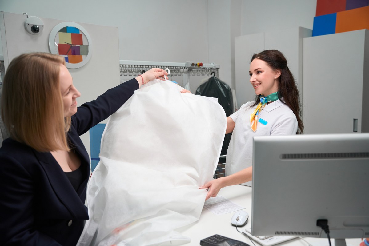 Woman gives dress to laundry staff for cleaning.