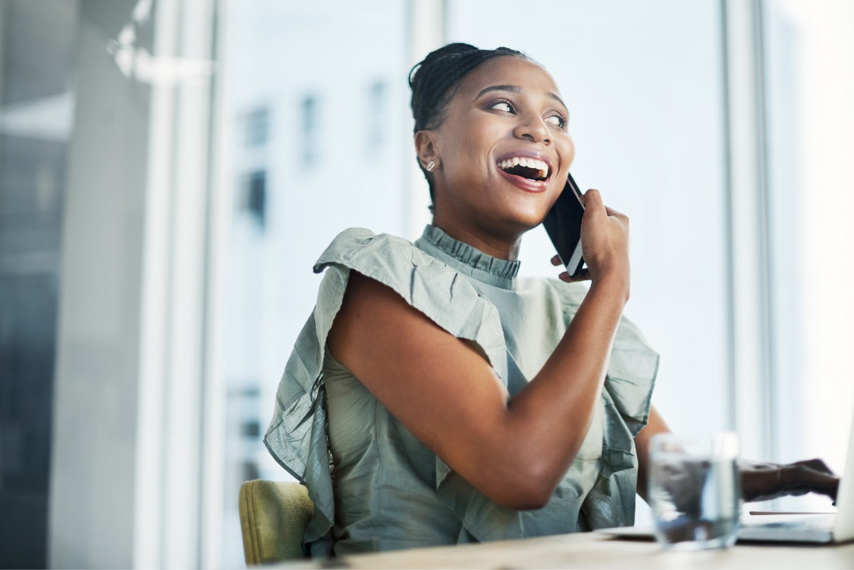 Woman happily talks to client on phone.