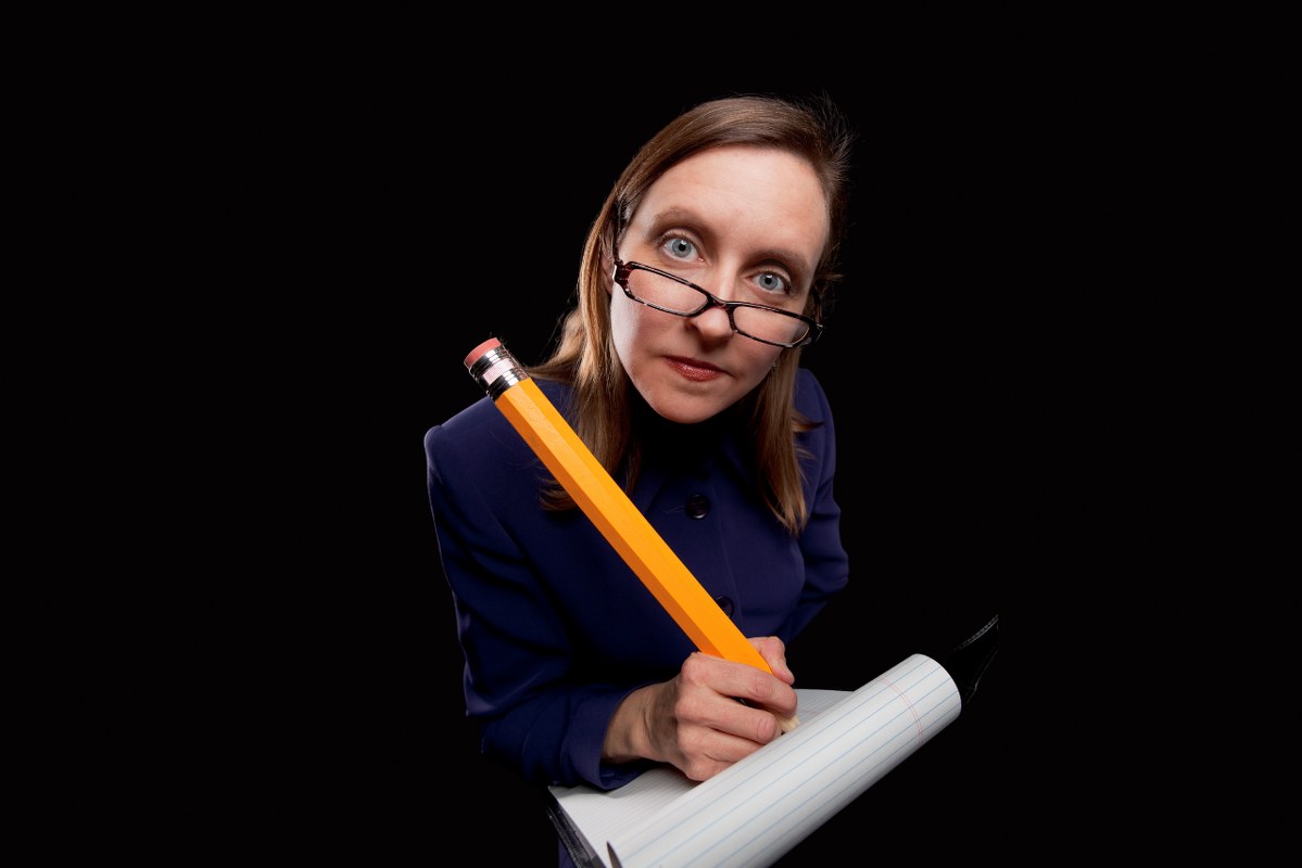 Woman taking notes with oversized pencil in hand.