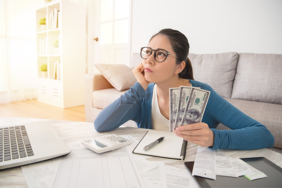 Woman worried while holding a few dollar bucks.