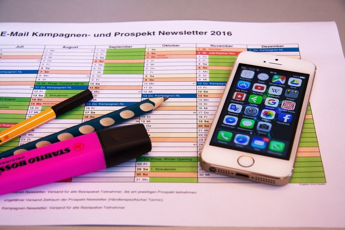 Writing material and a phone placed on a printed-out schedule.