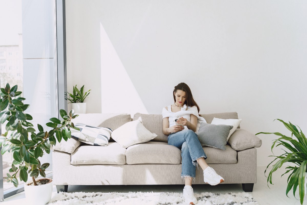 Young Woman sitting on the couch, looking after house while owners are gone.