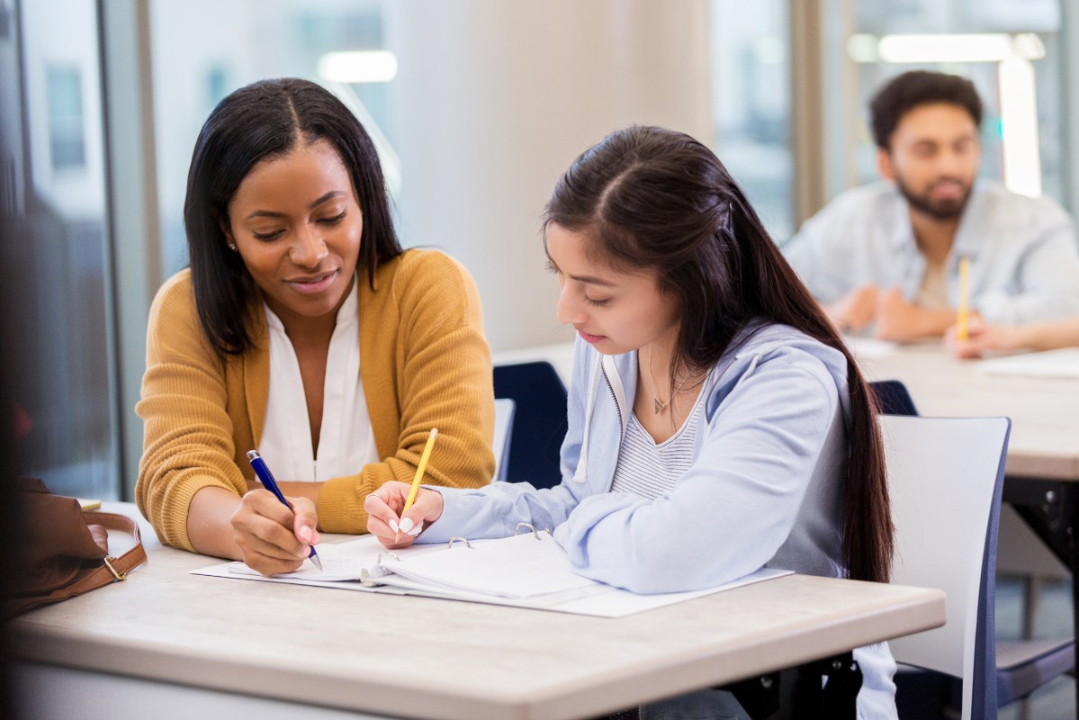 Young female adult doing one-on-one tutoring with student during class.