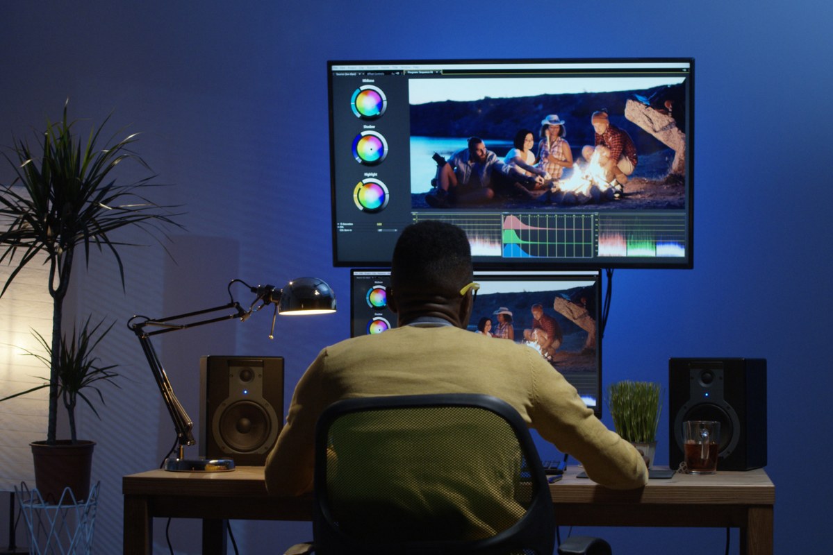 Young man sitting back and editing a video inside a room.