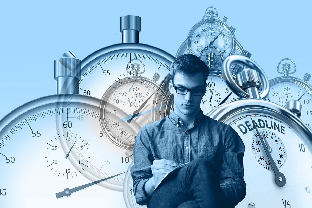 A man sitted infront of a background made of stopwatches.