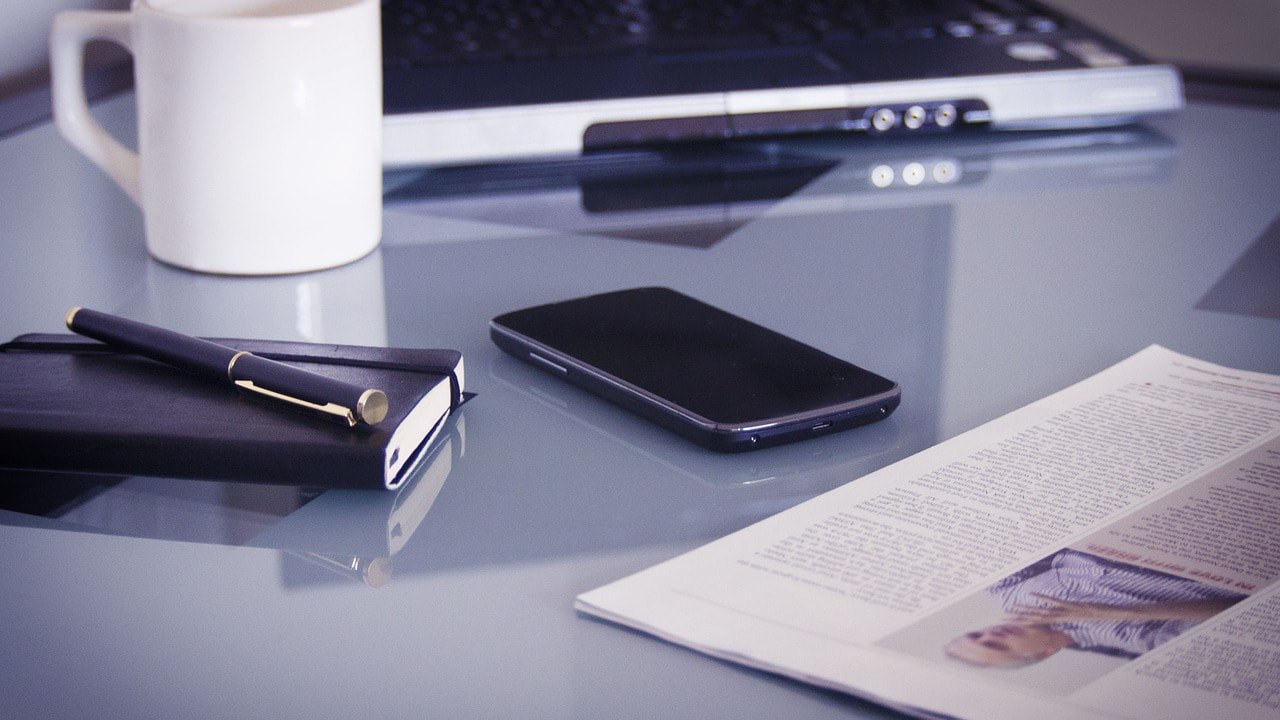 A mug, a phone and a notebook for working.