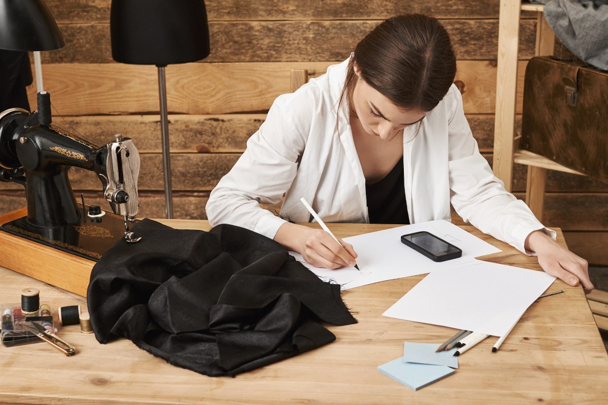 A woman is calculating the cost of producing clothes.