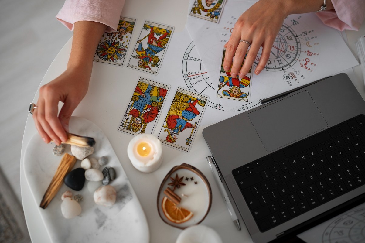 A woman is reading tarot cards with her laptop.