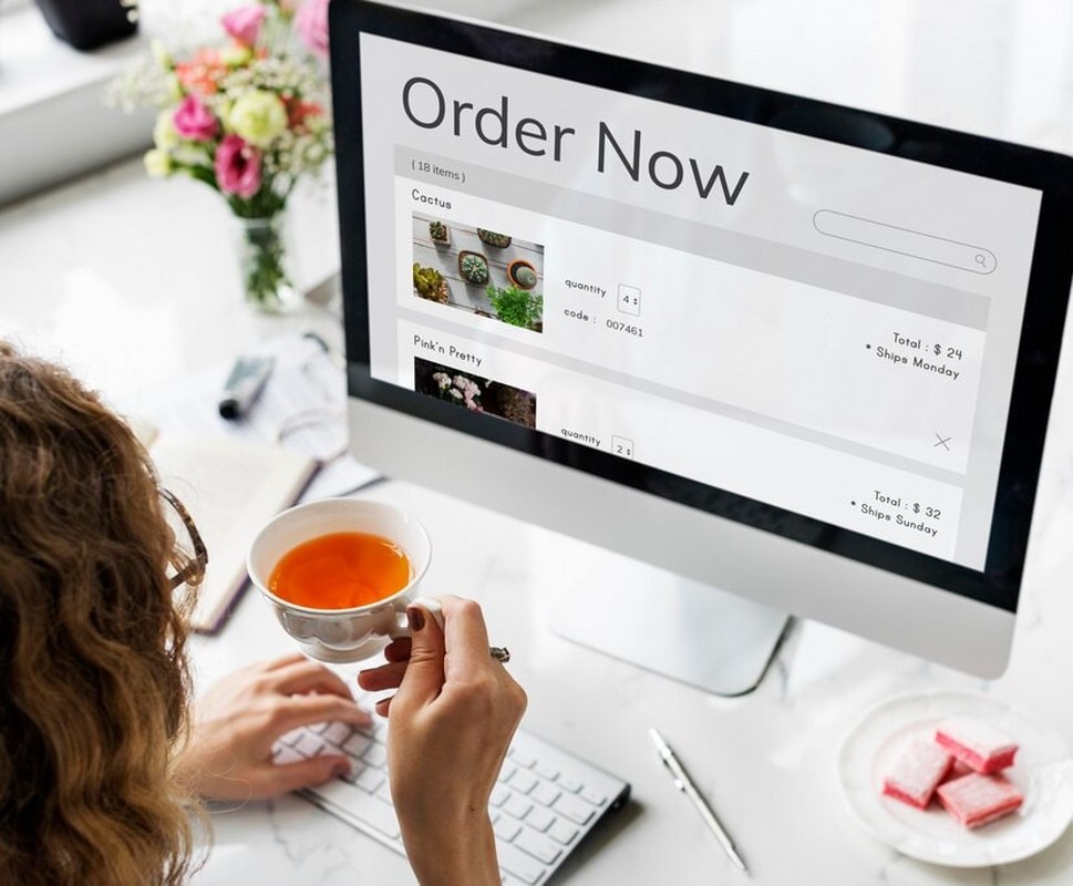 A woman looks at a monitor displaying a web store cart.