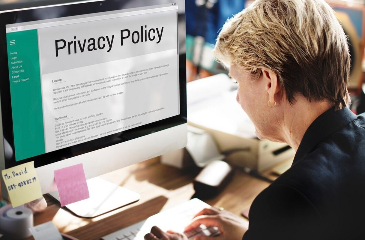 A woman stares at a monitor displaying a privacy policy.