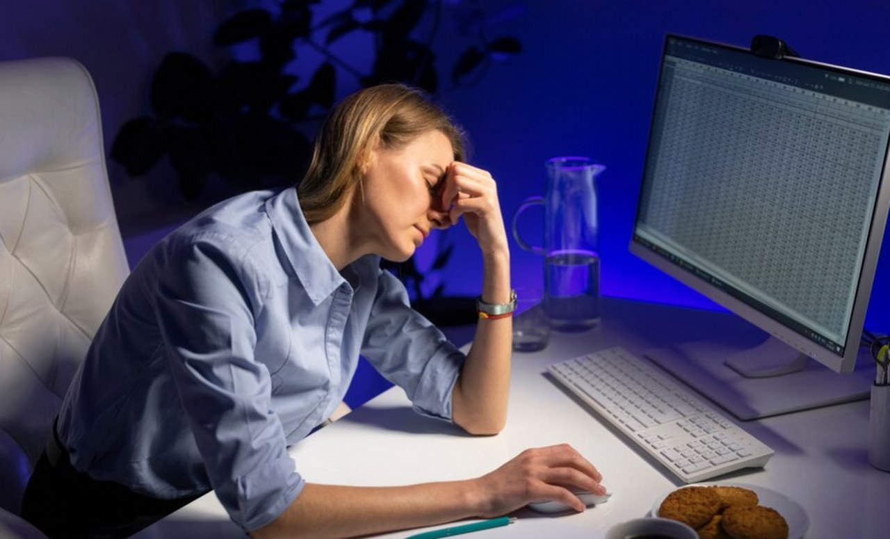 An unhappy woman working on her computer late at night.
