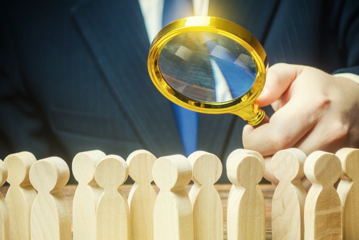Businessman is studying a crowd of people with a magnifying glass.