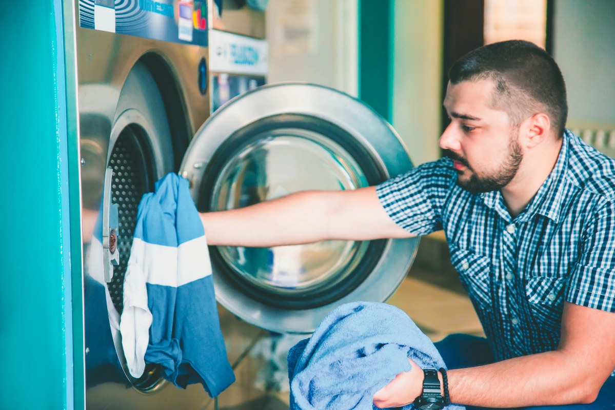 Busy male worker doing self-service laundry.