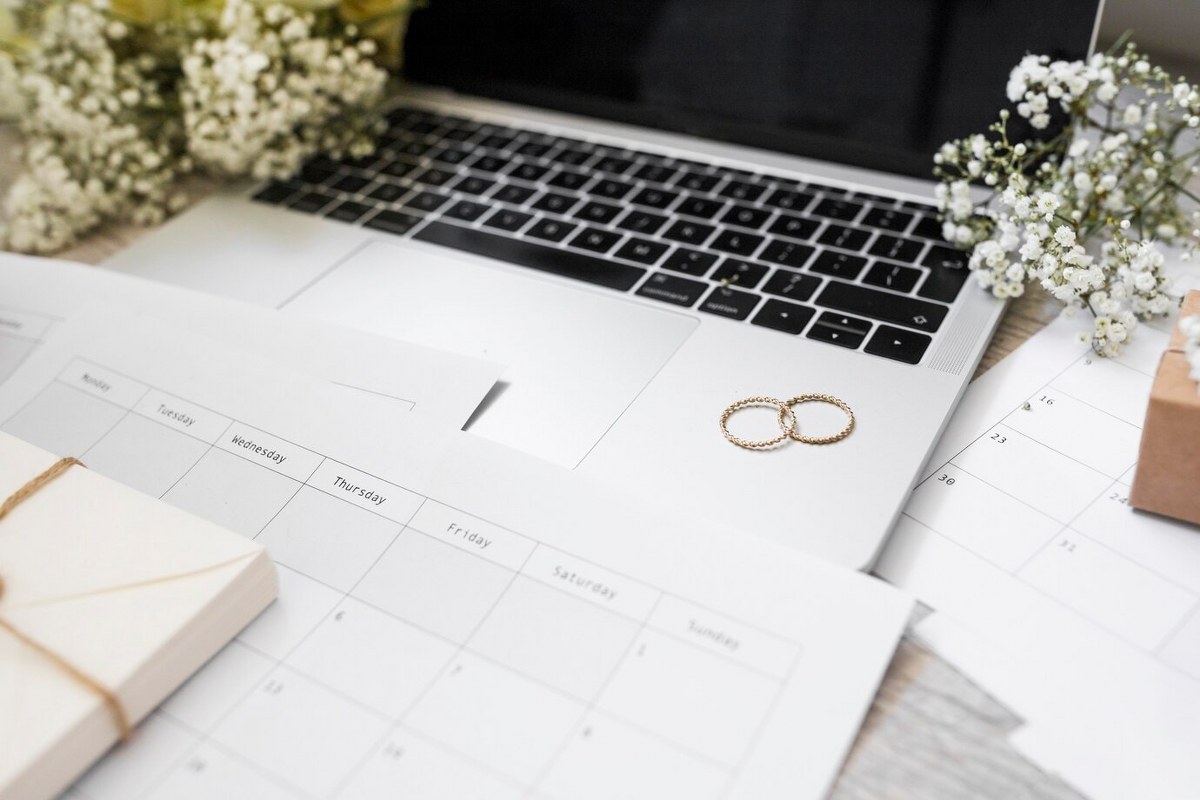 Calendar, wedding rings, baby's-breath flowers and a laptop.