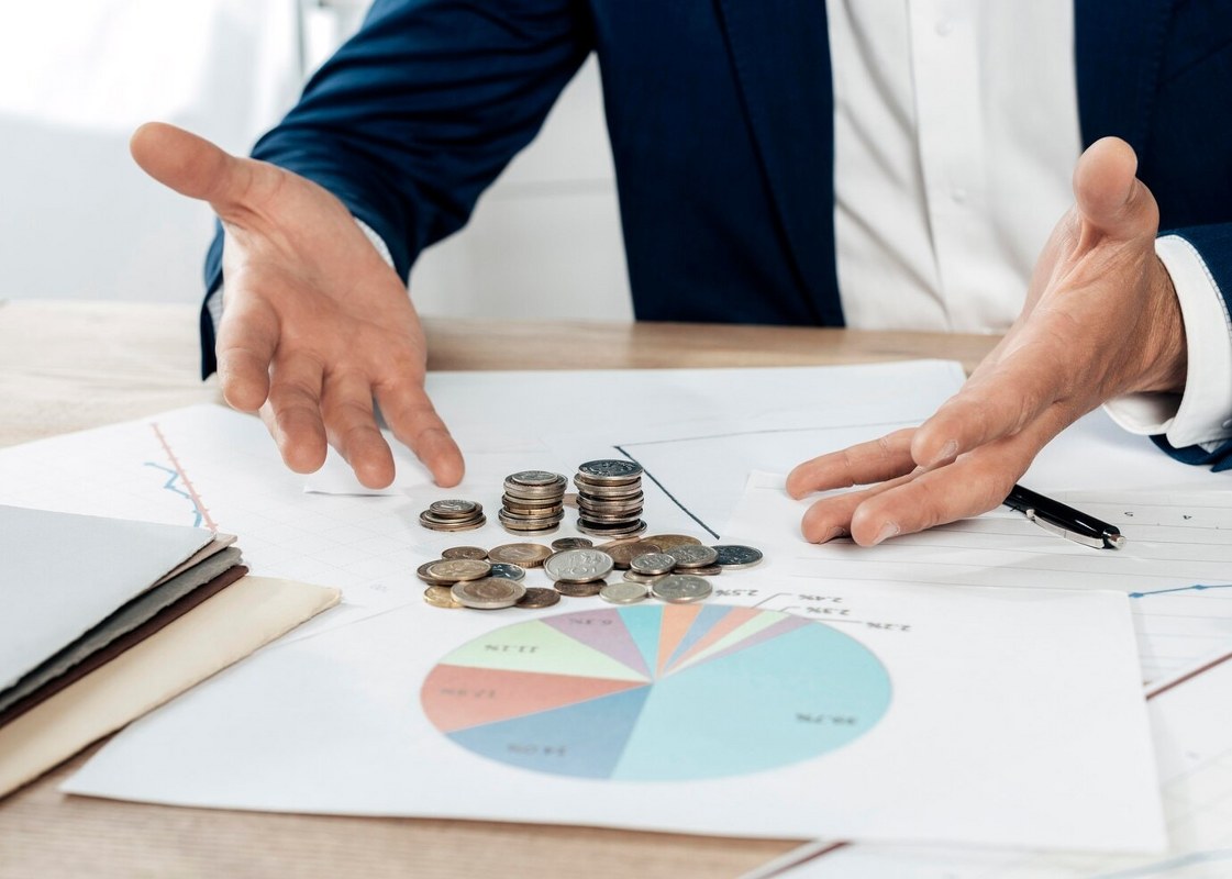 Close-up of a man with coins and statistics report.