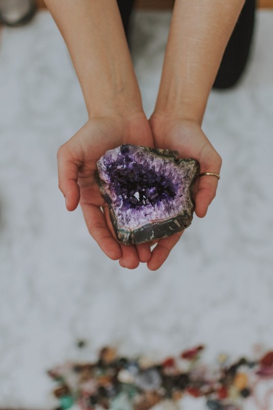 Closeup shot of a girl holding a multicolored rock in her hands.