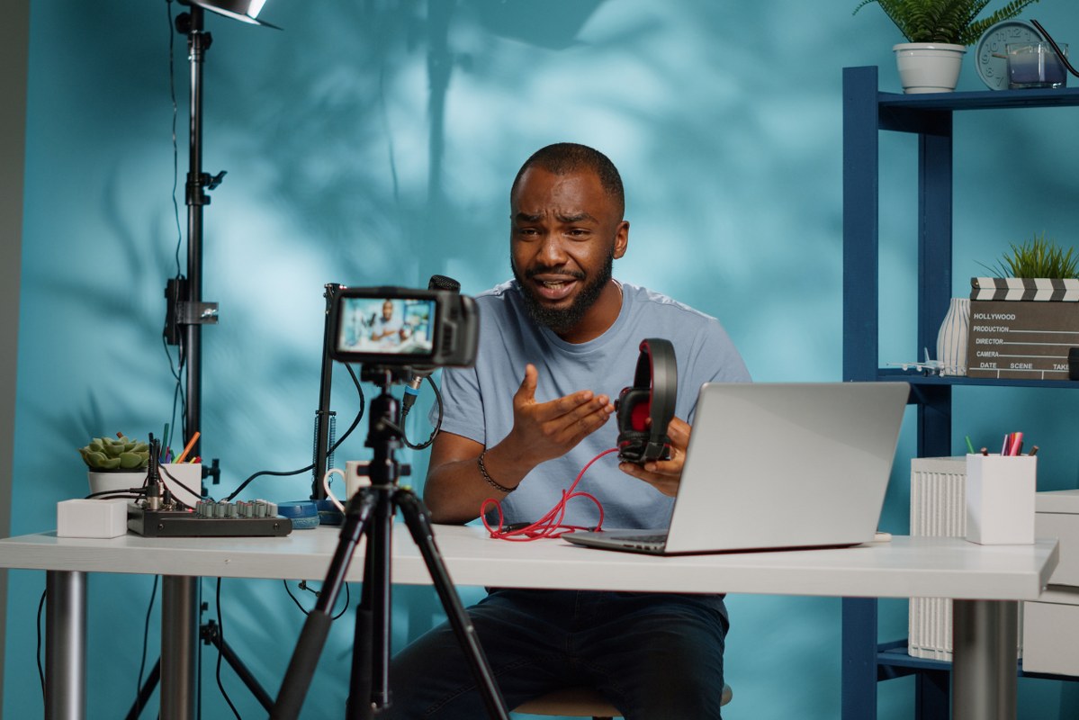 Content creator holding headphones for product review.