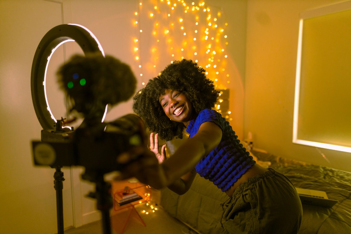 Content creator using phone and ring light for shooting a video.