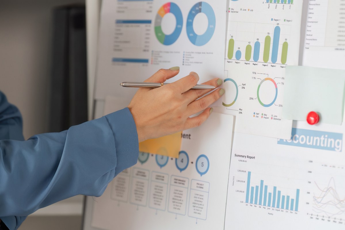 Diverse woman highlighting key metrics on business performance charts.