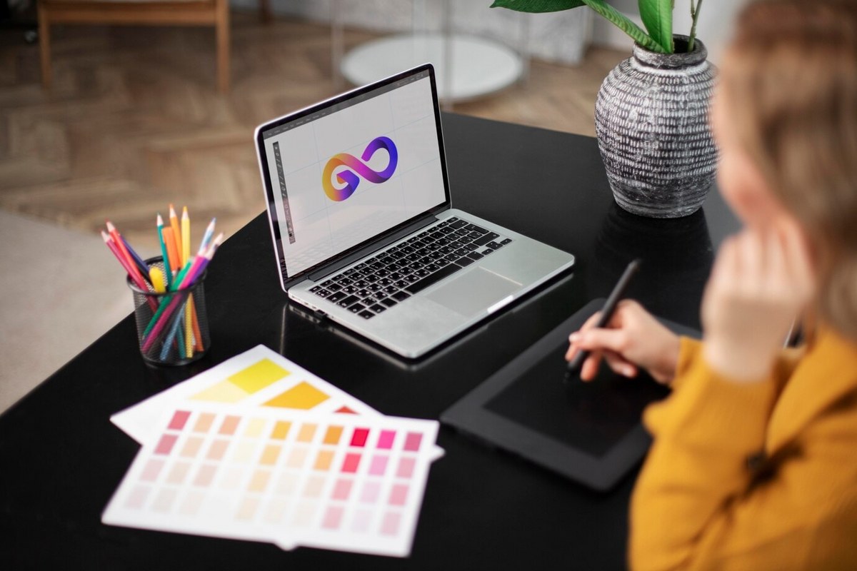 Female logo designer working on her tablet connected to a laptop.
