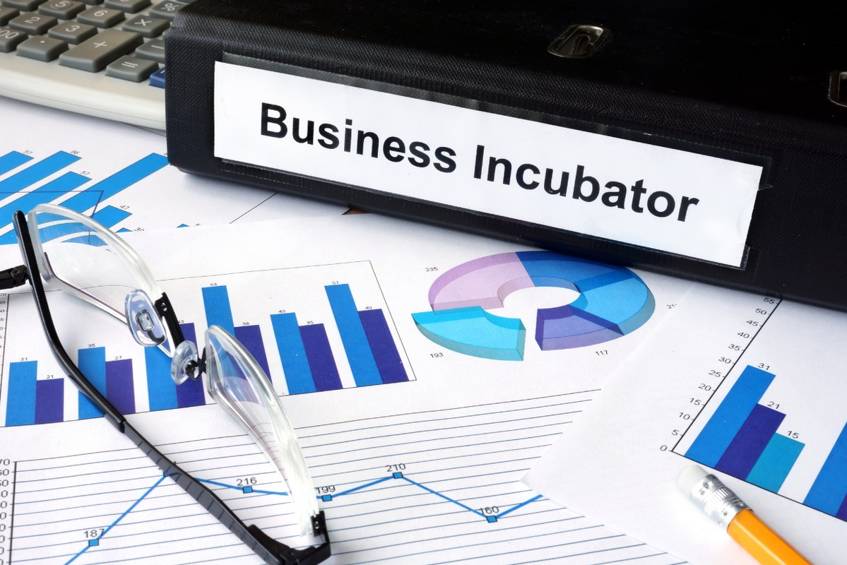 File folder with words Business Incubator and financial graphs.