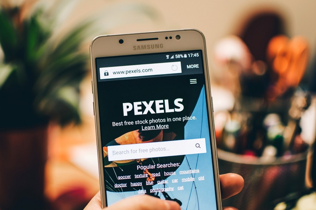 Hand holding a phone displaying the pexels website.