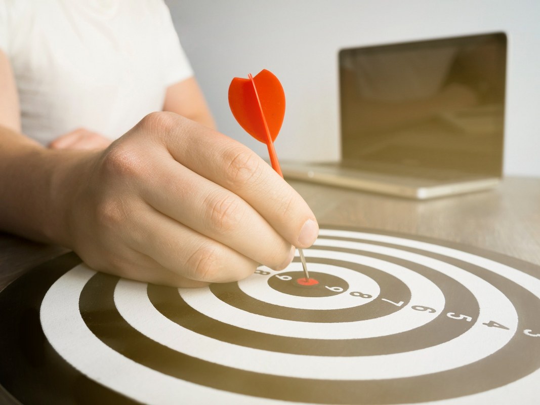 Hand holding dart on bull's-eye.