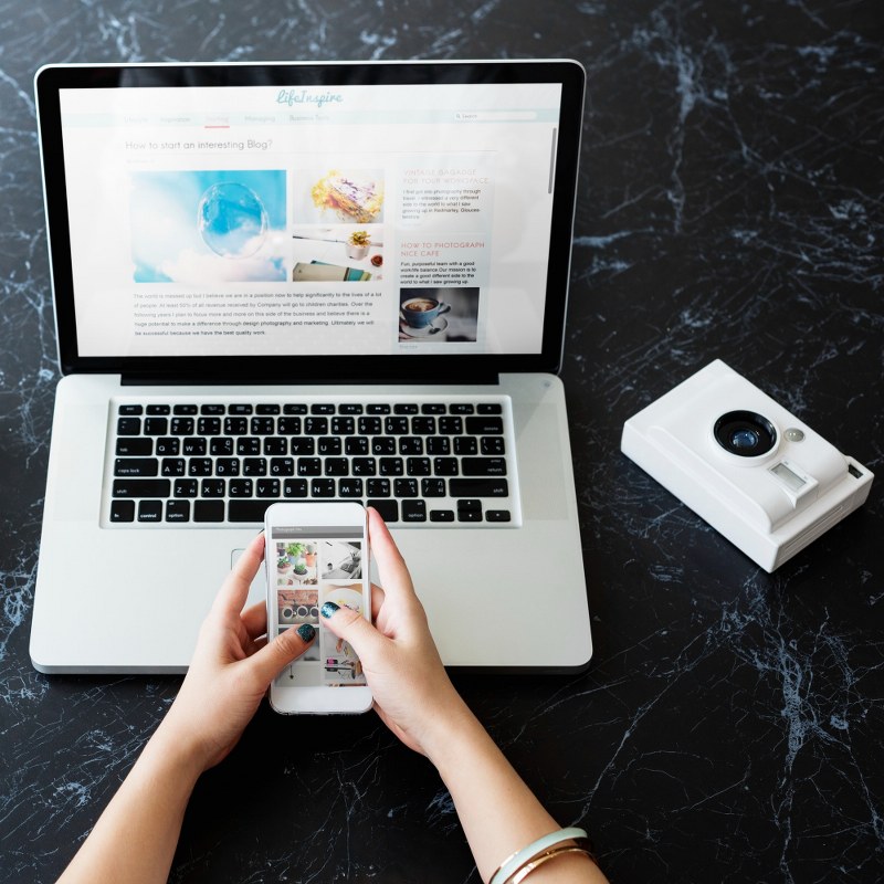 Hand is holding a phone in front of a laptop.