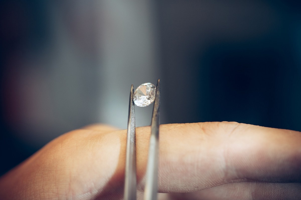 Jeweler holding diamond with tweezers.