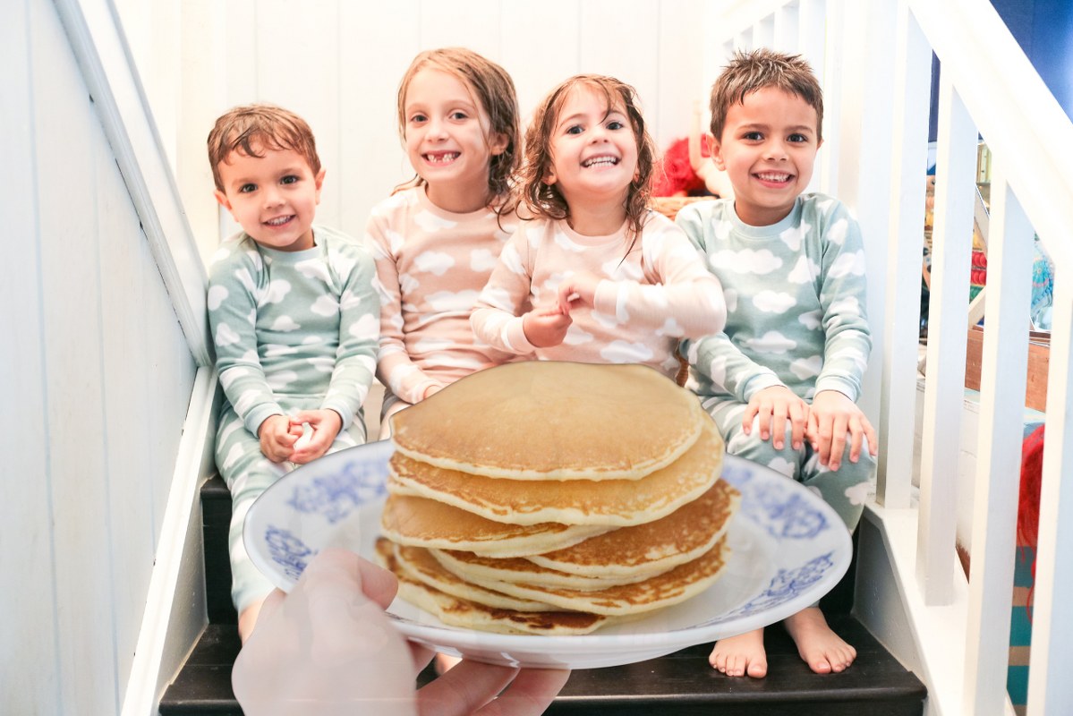 Kids in pajamas looking at pancakes.