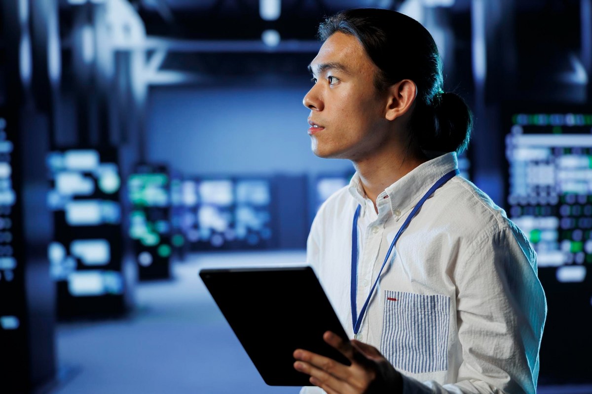 Man is monitoring his work while holding a tablet.