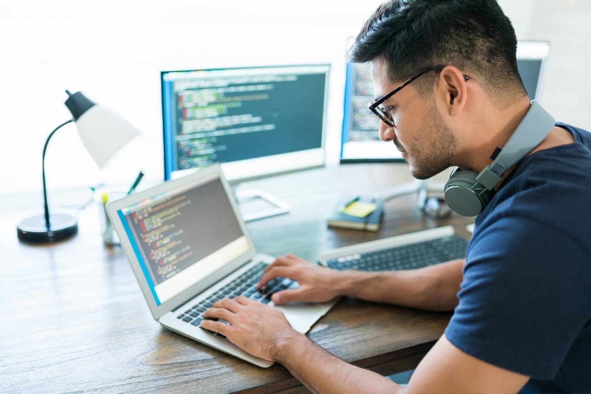 Man is working on coding using his laptop.
