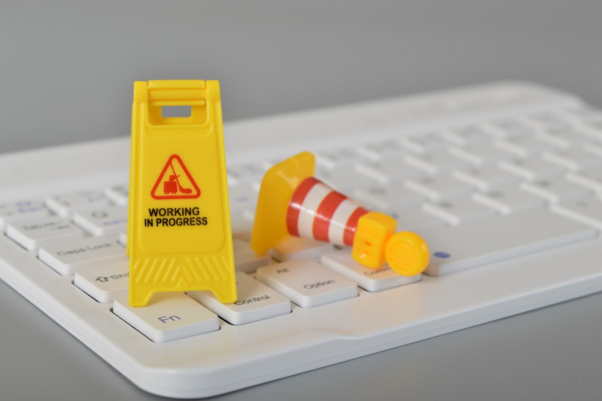 Miniature construction cones placed on top of a computer keyboard, symbolizing 'work in progress.'
