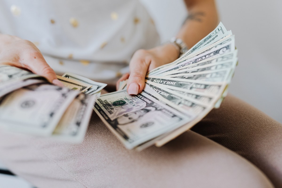 Person holding fan of US dollar bills.