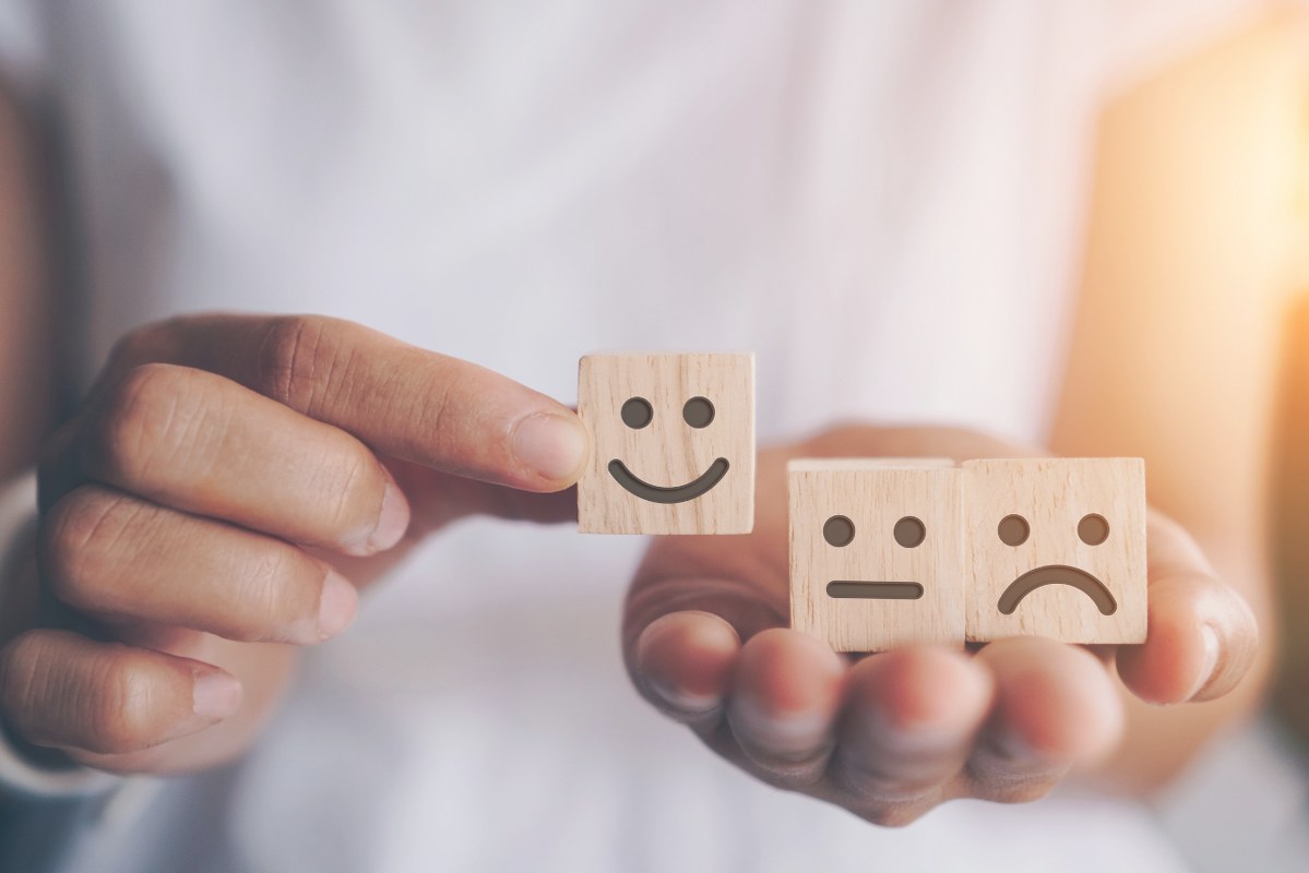 Person's Hands Holding Wooden Cubes with Various Emotions.