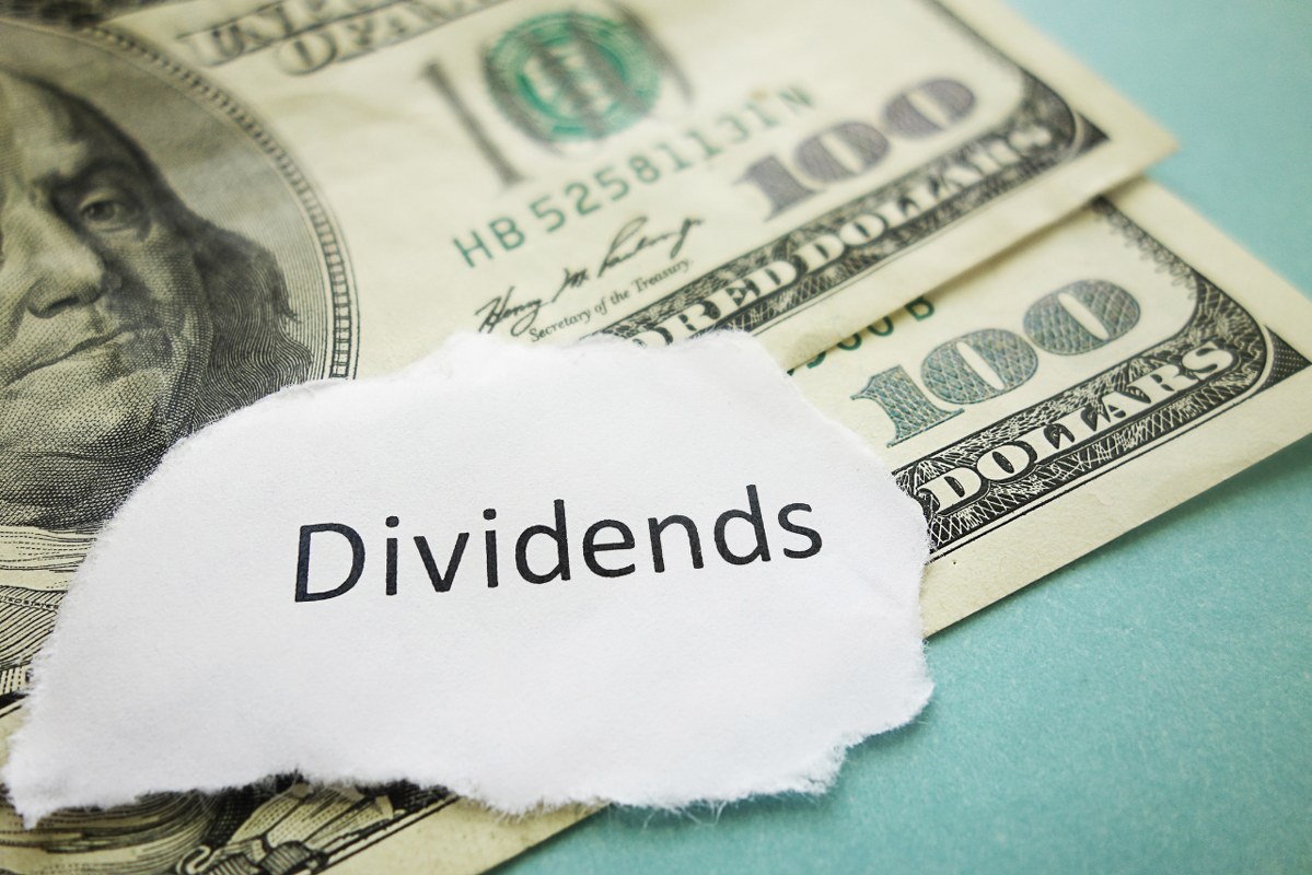 Piece of paper with Dividends word on top of cash.